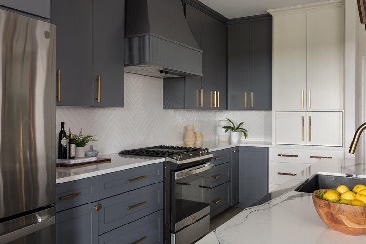 Kitchen seen from the refrigerator wall with charcoal cabinetry and white uppers in the Longwood project by Jennifer Kizzee Design