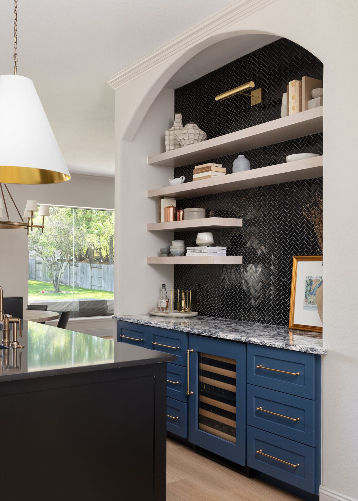 Bar with navy cabinetry, black herringbone tile and a wine refrigerator in the Markee Oaks project by Jennifer Kizzee Design