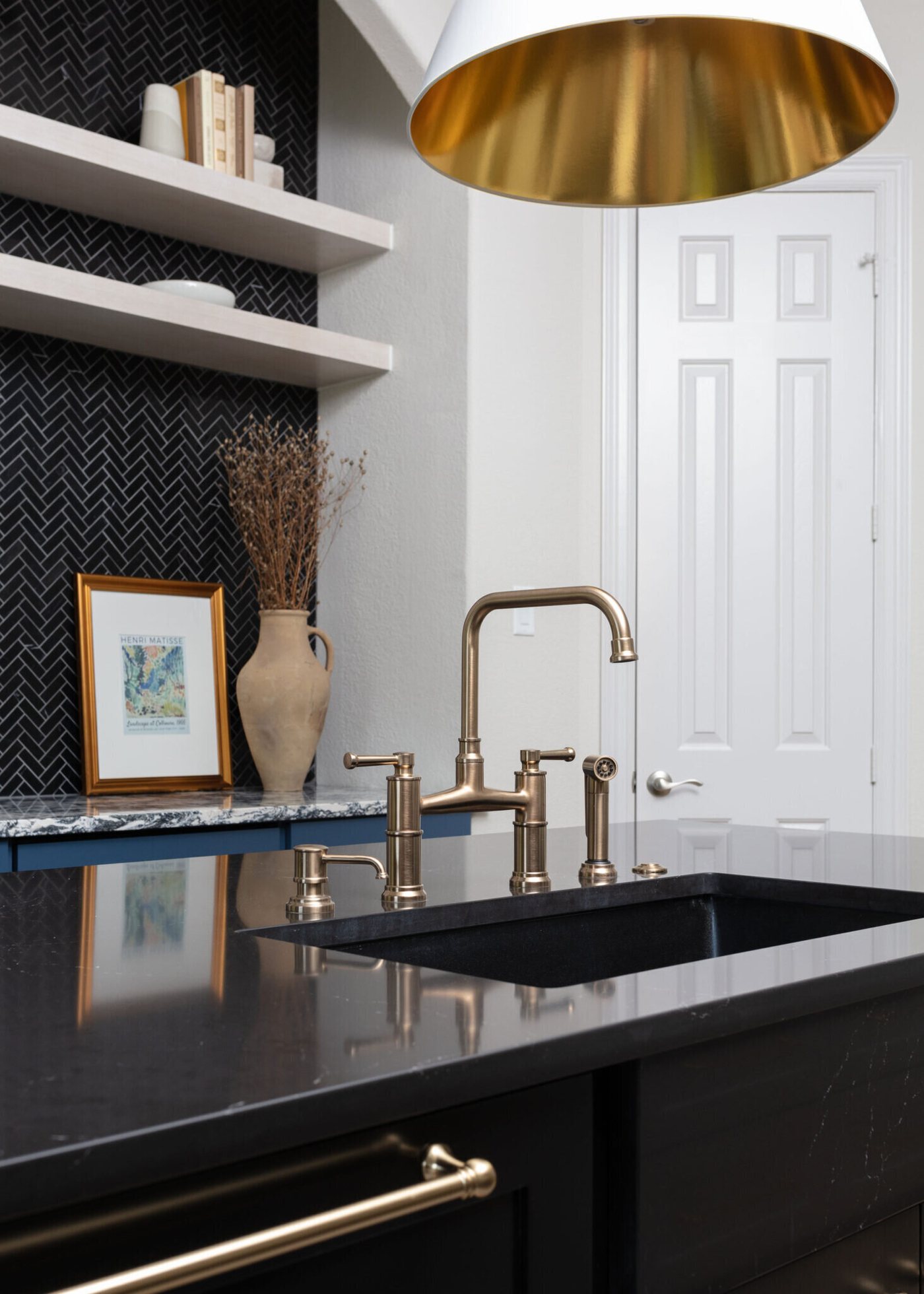 Brass faucet over a black undermount sink in the navy island in the Markee Oaks project by Jennifer Kizzee Design