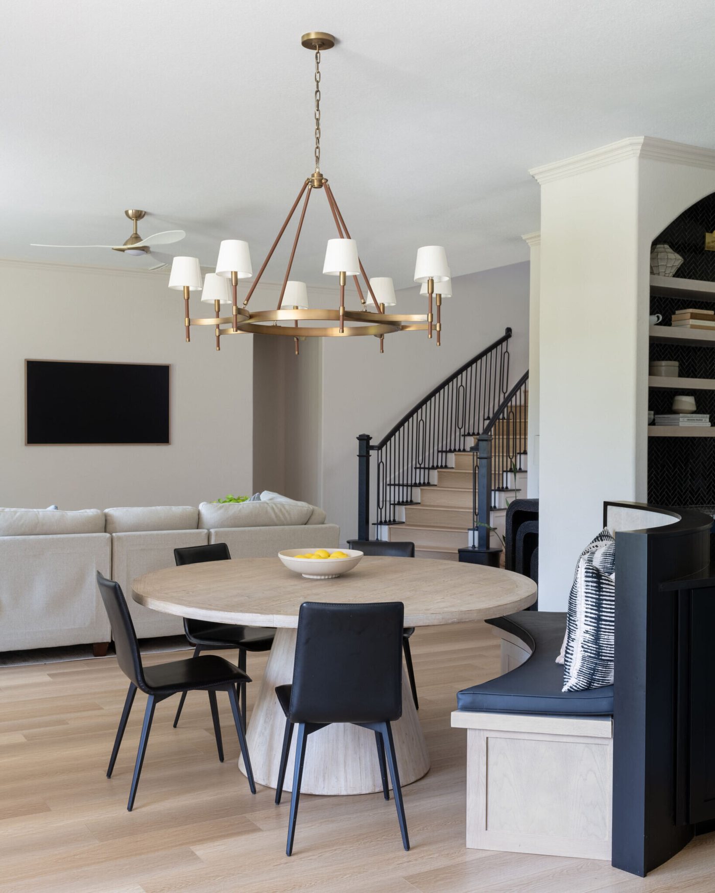 Dining area with a round table and black chairs open to the kitchen and staircase in the Markee Oaks project by Jennifer Kizzee Design