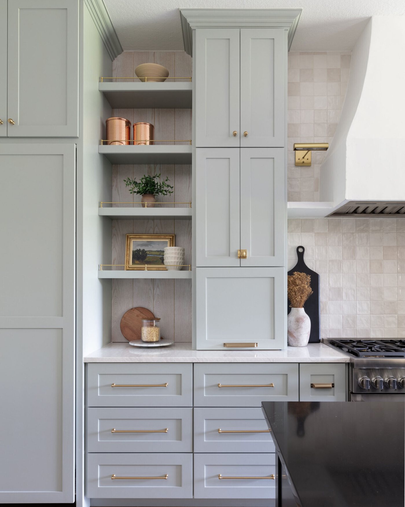 Greige cabinetry with open shelves beside a plaster hood over the range in the Markee Oaks project by Jennifer Kizzee Design