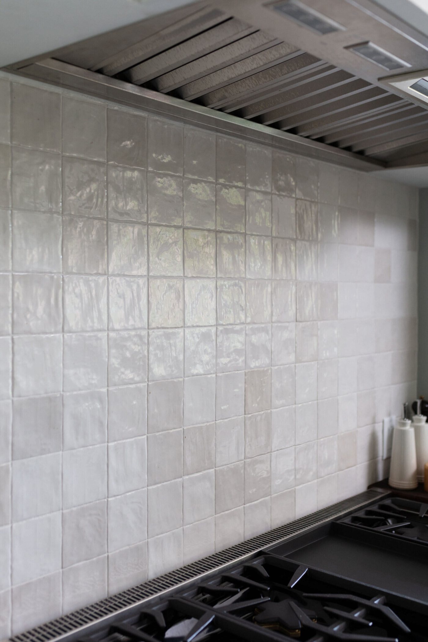 Pale zellige tile behind a gas range under a plaster hood in the Markee Oaks project by Jennifer Kizzee Design