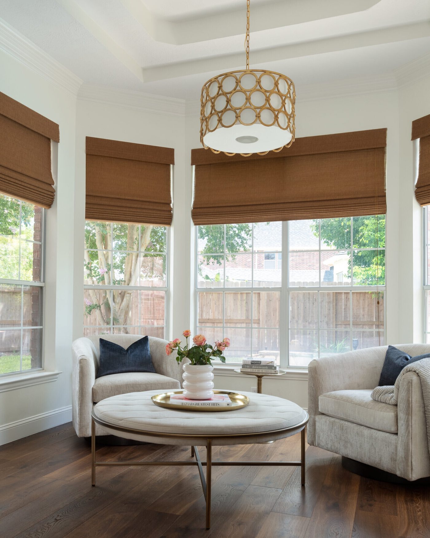 Sitting area with swivel chairs, a round table and woven shades at the windows in the Marrelli Project project by Jennifer Kizzee Design