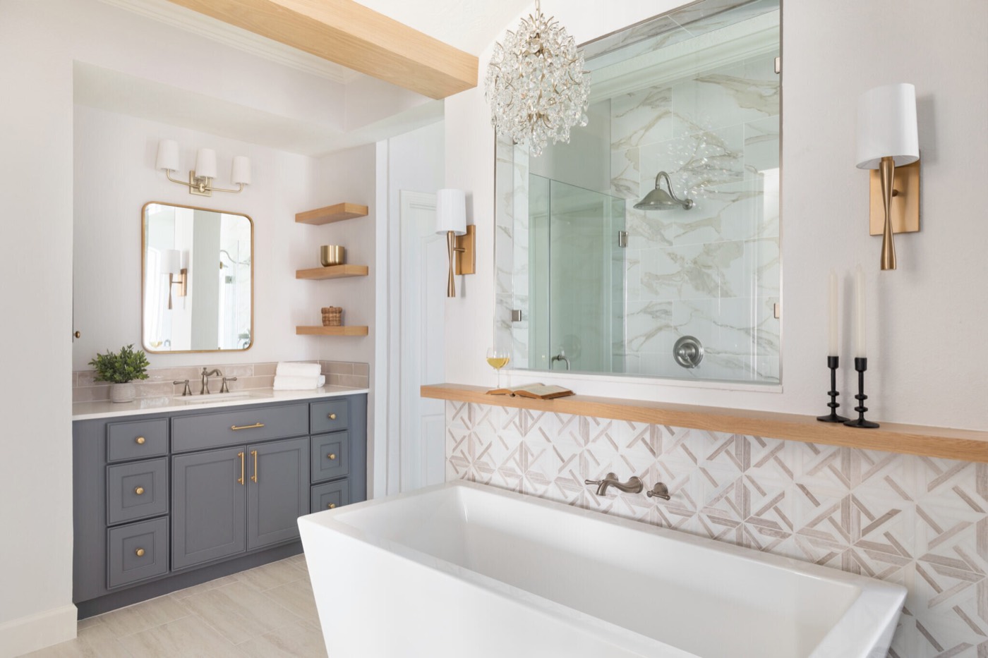 Freestanding tub against a geometric marble mosaic wall beside an interior window into the marble shower in the Mountain Falls Primary Bath project by Jennifer Kizzee Design