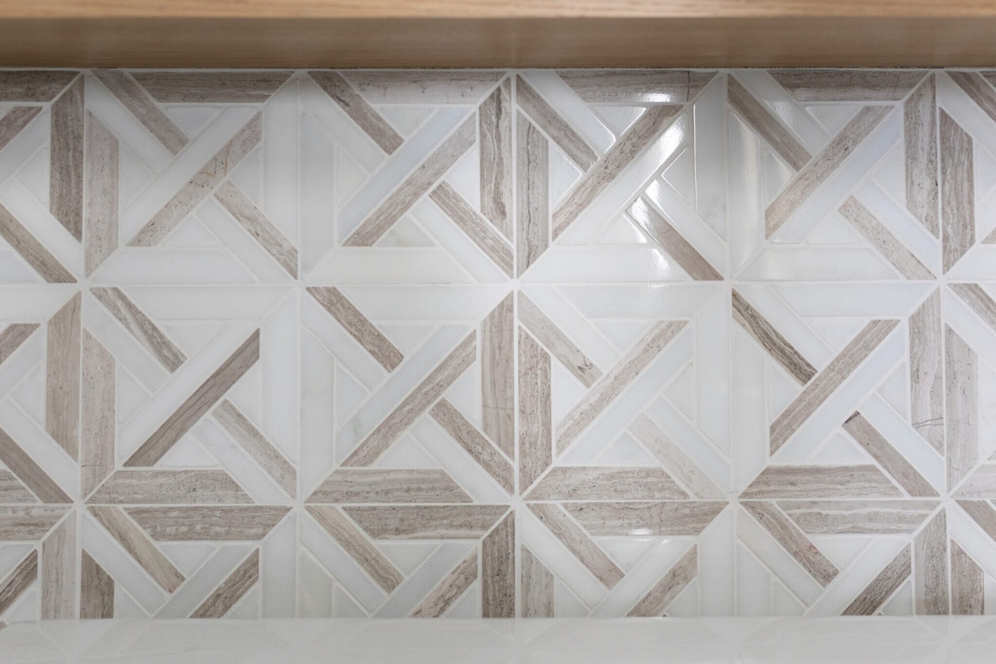 Geometric white and weathered taupe marble mosaic beneath a white oak ledge in the Mountain Falls Primary Bath project by Jennifer Kizzee Design