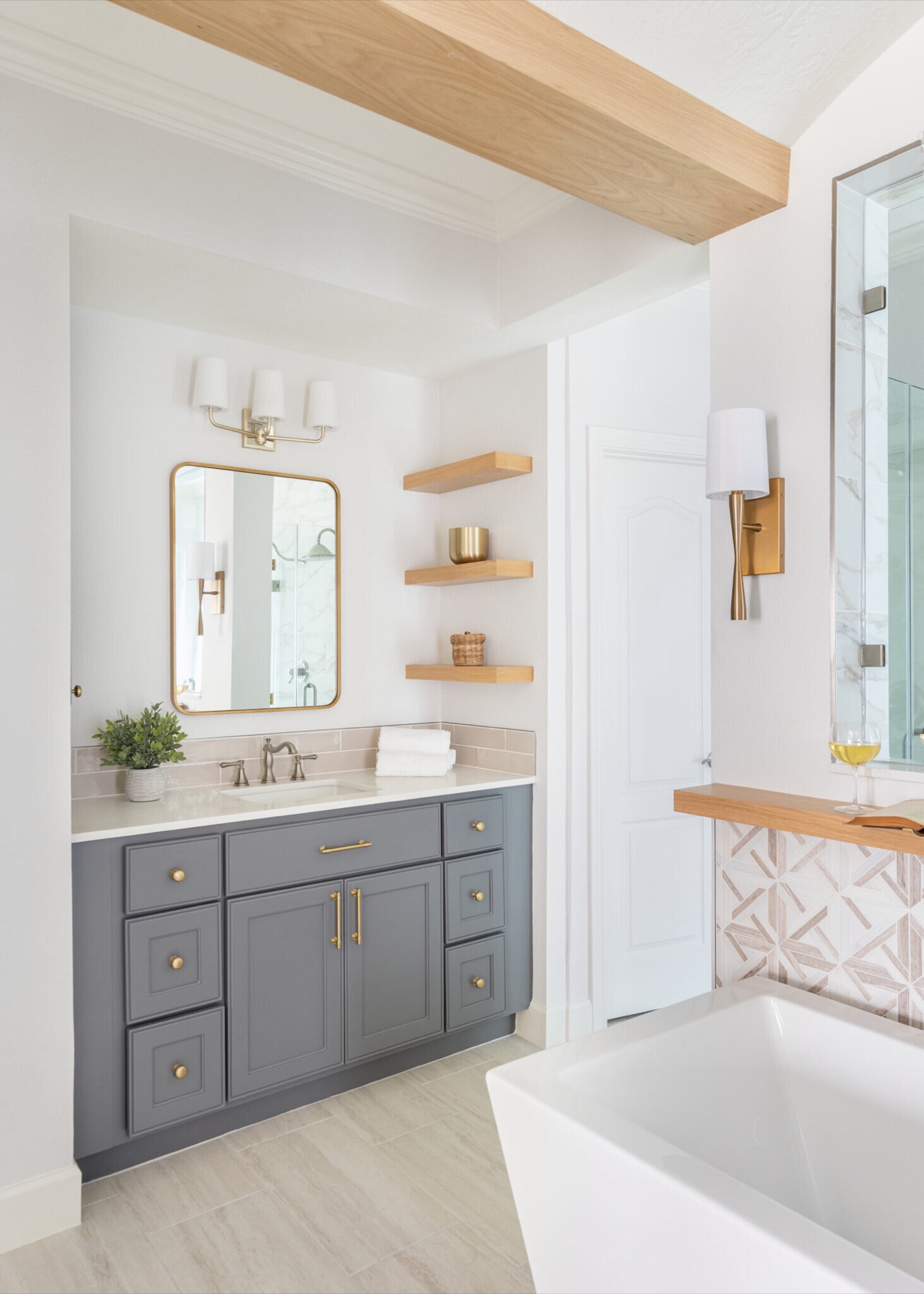 Vanity alcove with a gold arched mirror, white oak floating shelves and a slate gray vanity in the Mountain Falls Primary Bath project by Jennifer Kizzee Design