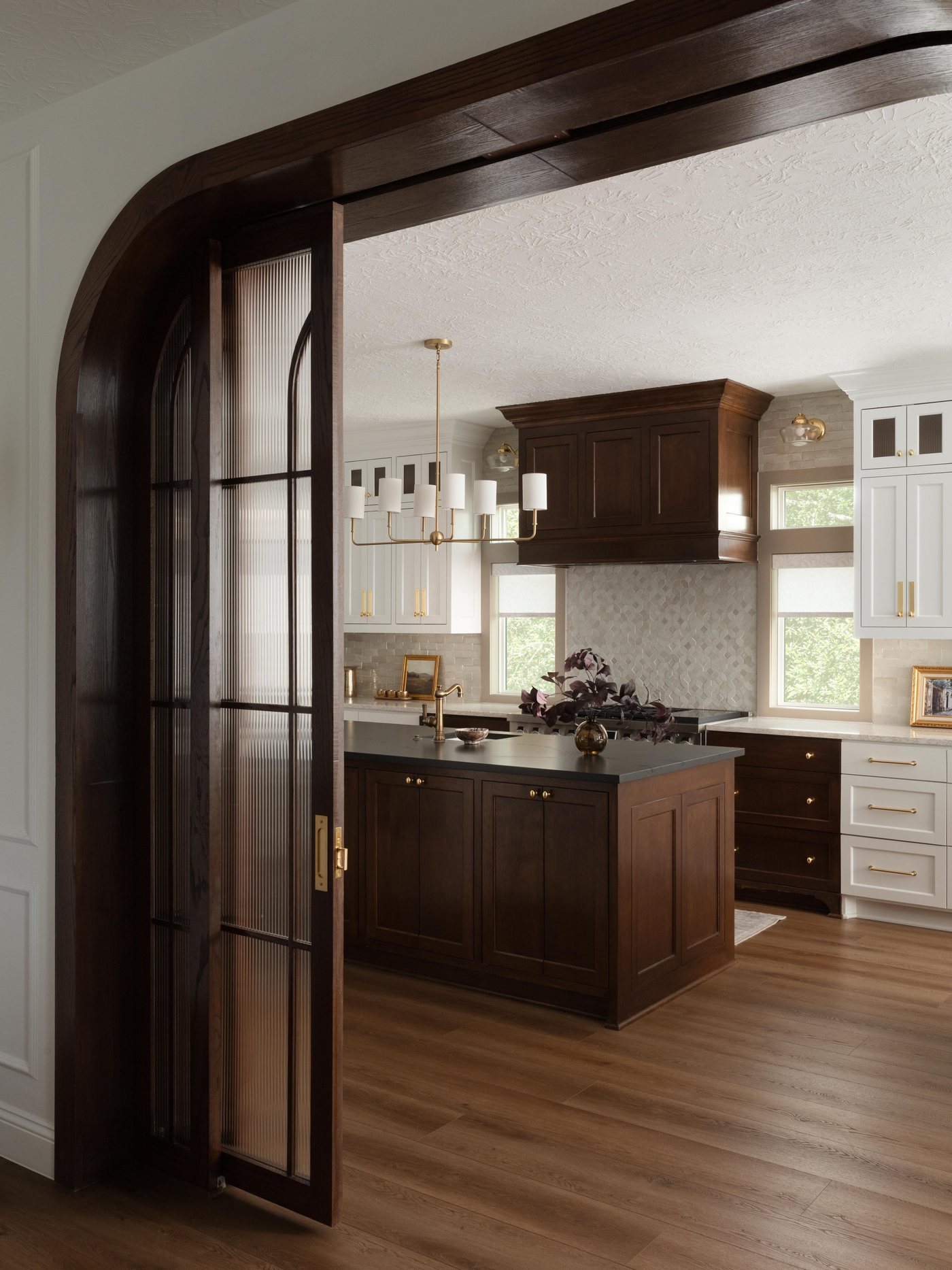Arched steel and glass doors opening to the kitchen in the Pebble Brook project by Jennifer Kizzee Design