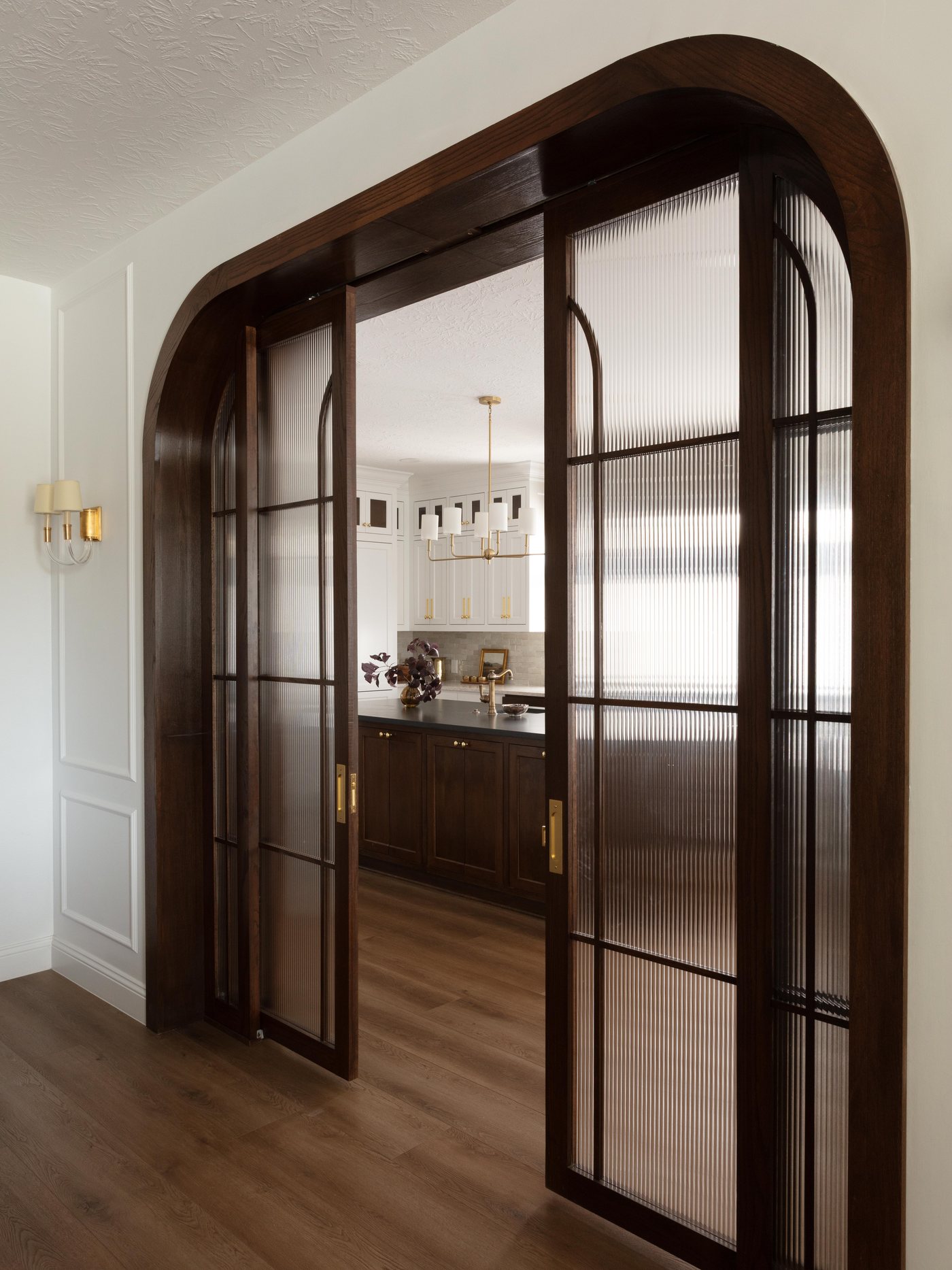 Arched steel and glass doors seen from the hall in the Pebble Brook project by Jennifer Kizzee Design