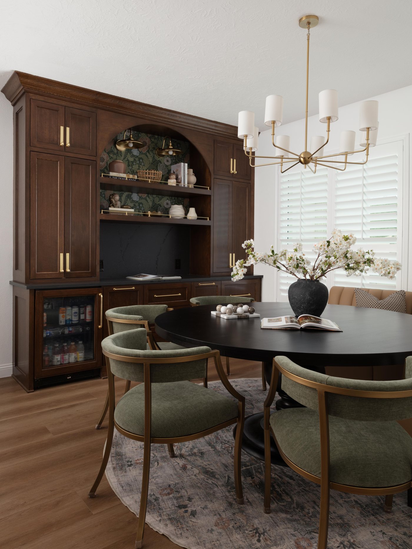 Dining room with stained built-ins, a lit arch and green upholstered chairs in the Pebble Brook project by Jennifer Kizzee Design