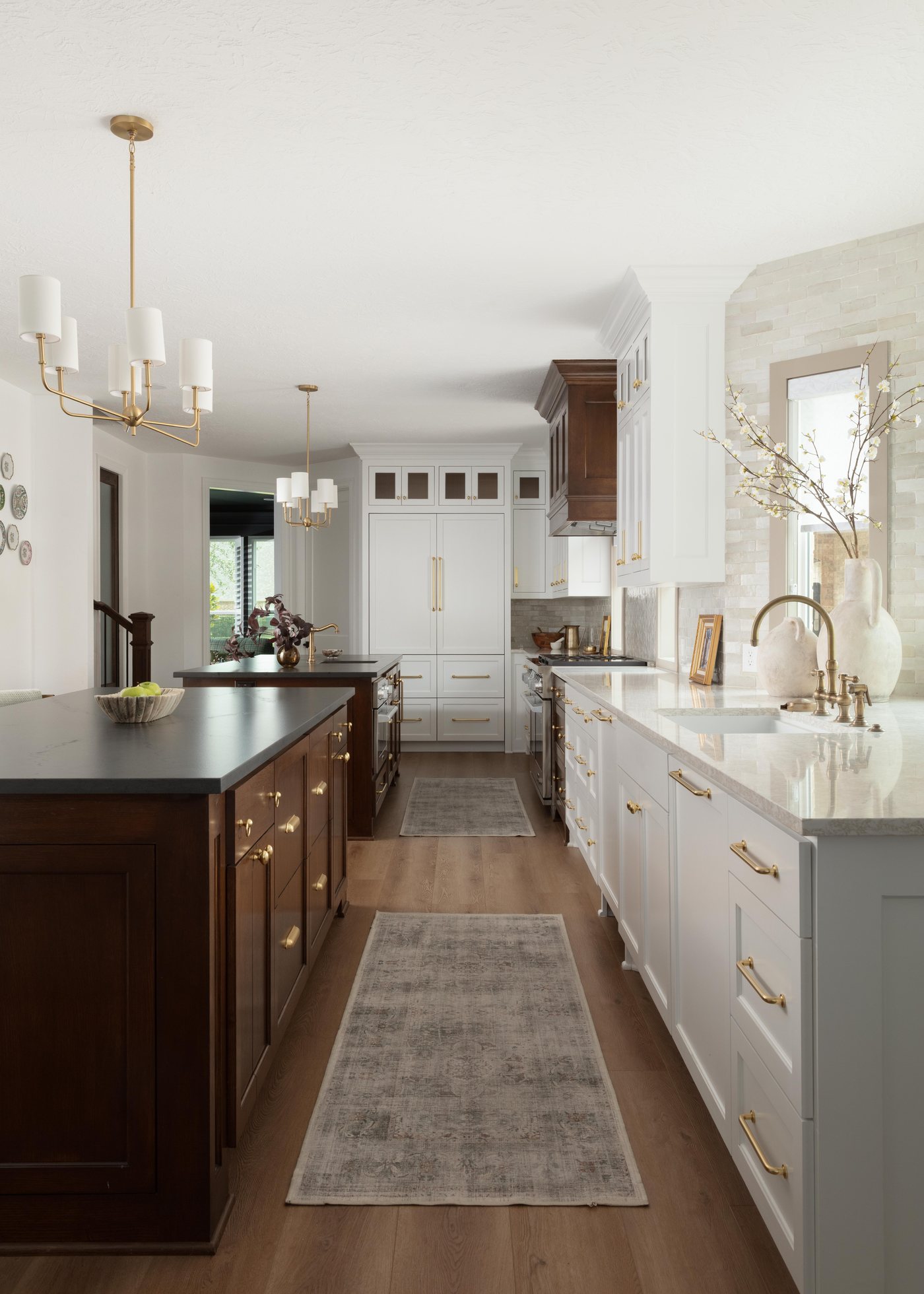 Kitchen seen down the runner with white cabinetry on one side and stained wood on the other in the Pebble Brook project by Jennifer Kizzee Design