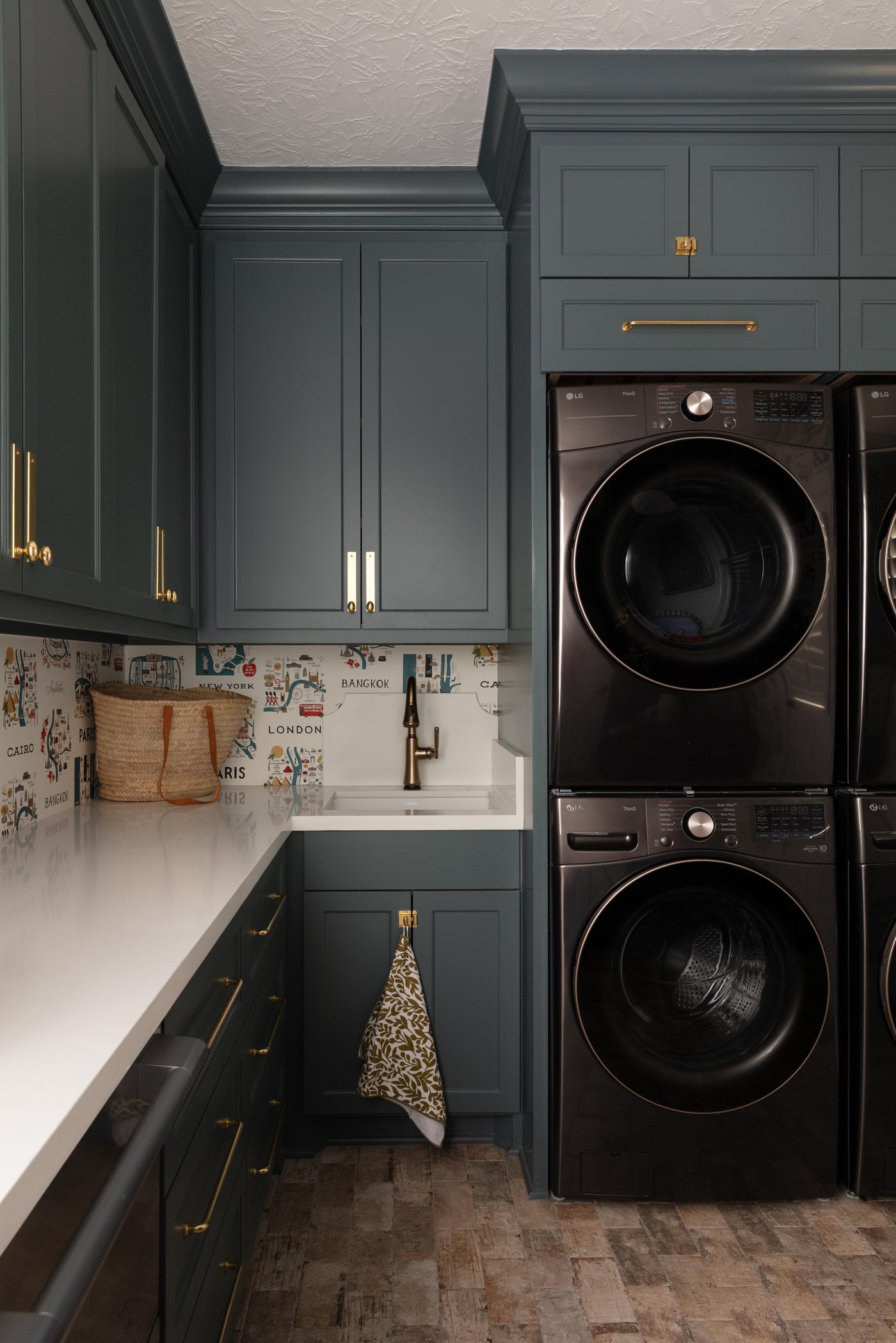 Stacked black washer and dryer in teal cabinetry with a folding counter in the Pebble Brook project by Jennifer Kizzee Design