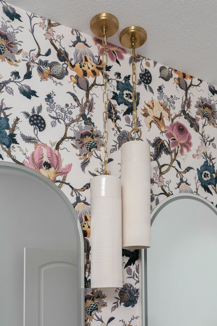 Floral wallpaper behind an arched niche and a brass sconce in the Pine Lodge project by Jennifer Kizzee Design