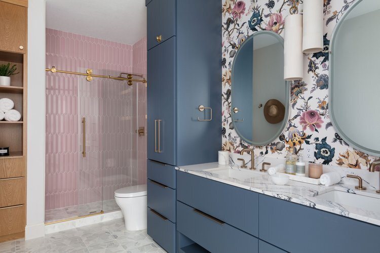 Navy vanity beside a pink tiled shower under floral wallpaper in the Pine Lodge project by Jennifer Kizzee Design