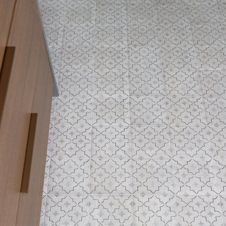 Patterned floor tile meeting the marble shower curb in the Pine Lodge project by Jennifer Kizzee Design