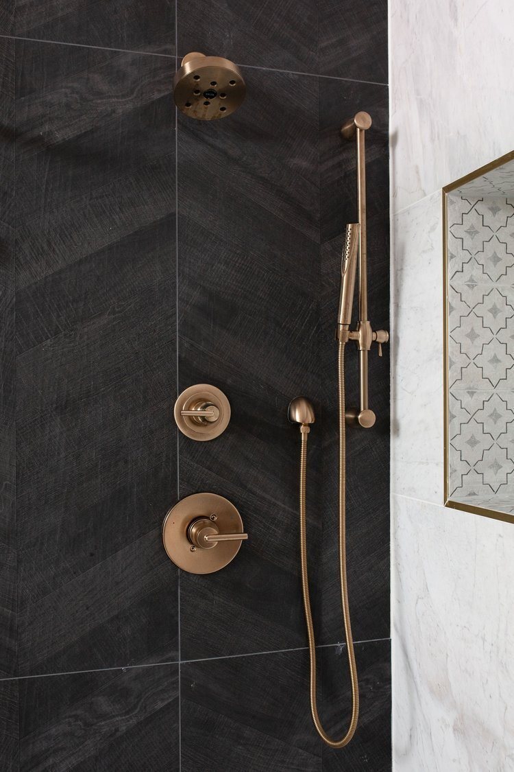 Shower in black stone and marble with gold fittings in the Pine Lodge project by Jennifer Kizzee Design