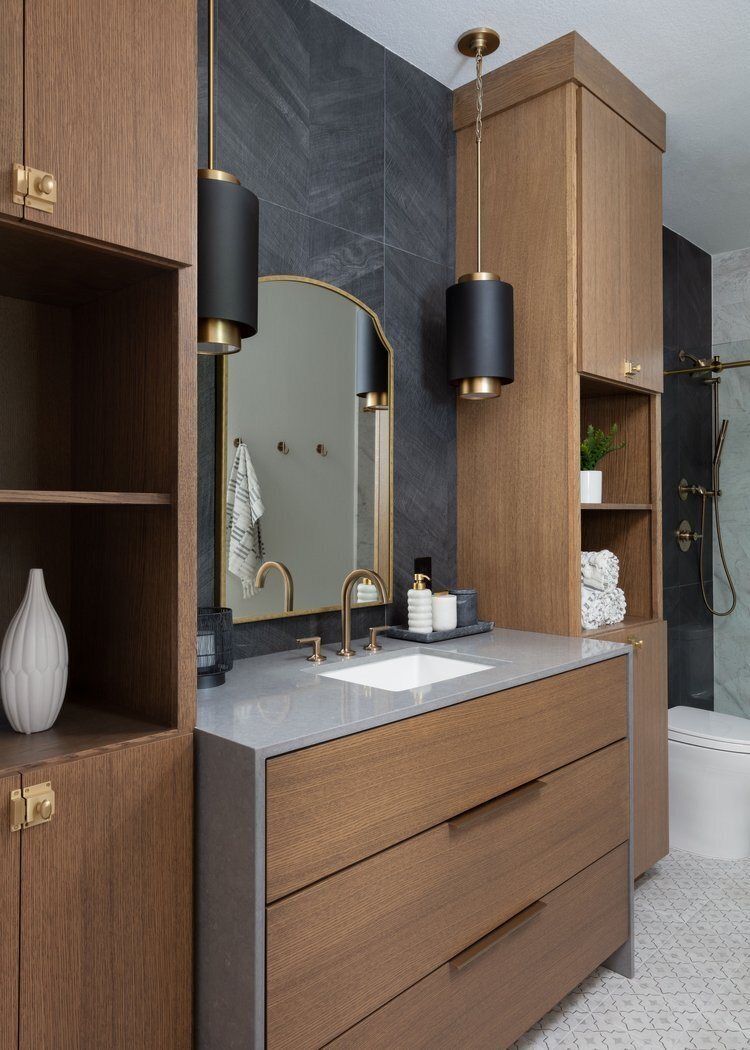 White oak vanity and tall storage against a black stone wall in the Pine Lodge project by Jennifer Kizzee Design