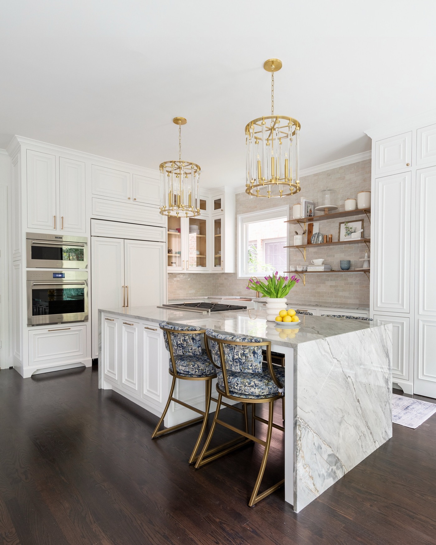 Kitchen appliance wall of stainless double ovens and panel ready refrigeration beside the stone waterfall island in the Pinewold Kitchen project by Jennifer Kizzee Design