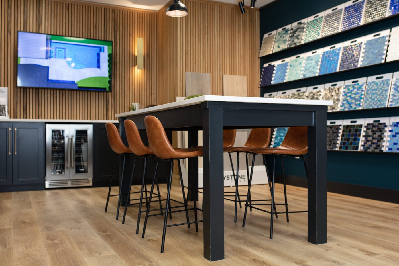 Black table with leather stools between the sample wall and the screen in the Pool Envy project by Jennifer Kizzee Design