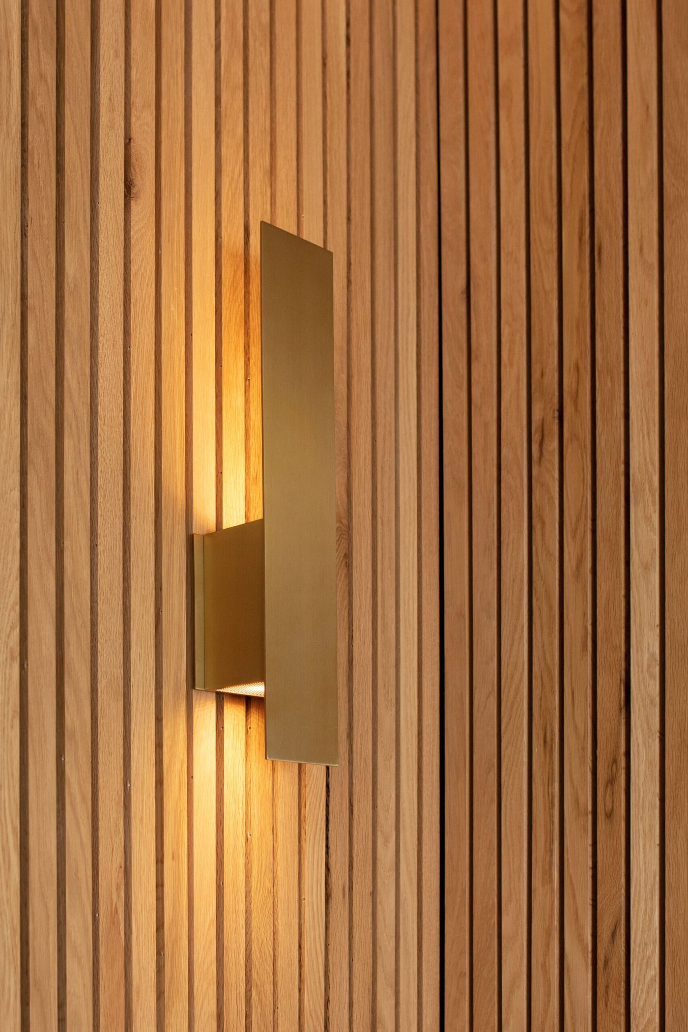 Brass linear sconce mounted on the wood slat wall in the Pool Envy project by Jennifer Kizzee Design