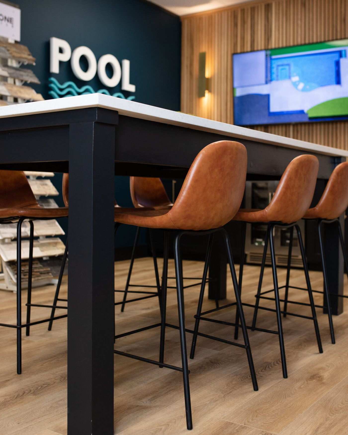 Leather stools pulled up to the black selection table in the Pool Envy project by Jennifer Kizzee Design
