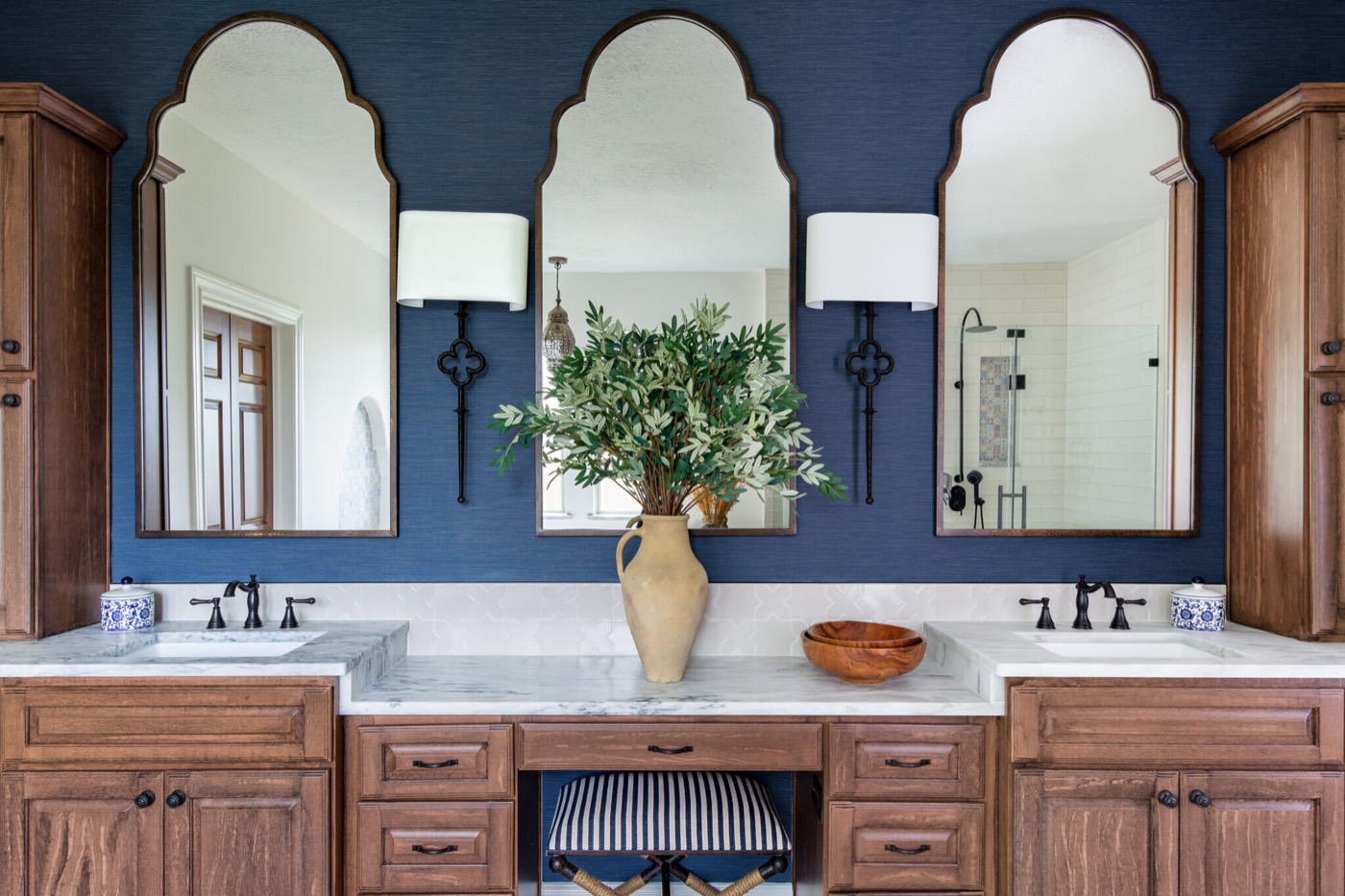 Primary bathroom double vanity with three arched wood-framed mirrors on a navy grasscloth wall in the Rockpoint project by Jennifer Kizzee Design