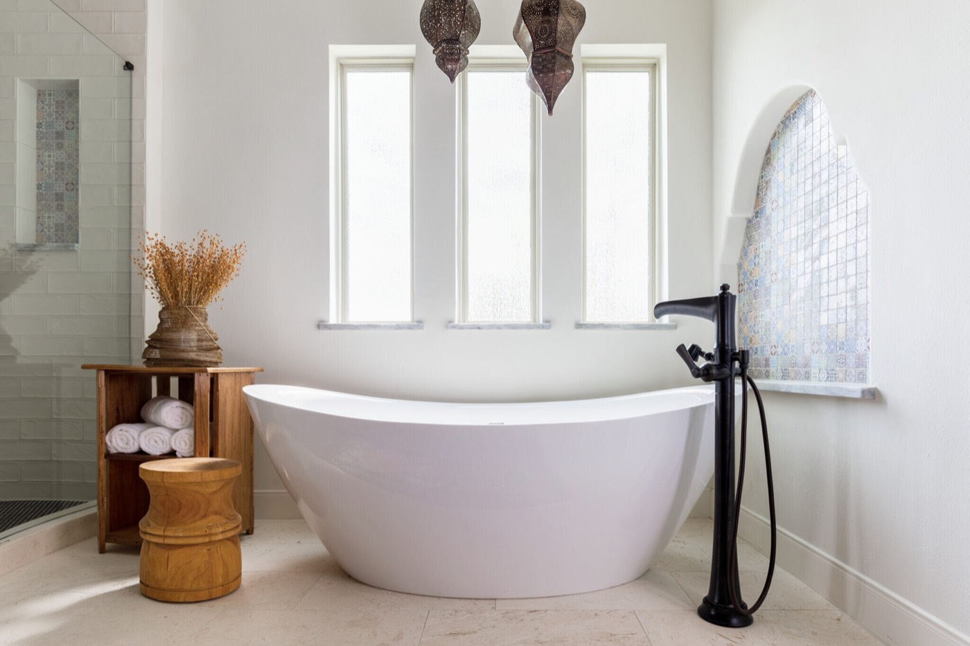 Primary bathroom with a freestanding tub centered under three windows and a matte black floor-mount tub filler in the Rockpoint project by Jennifer Kizzee Design