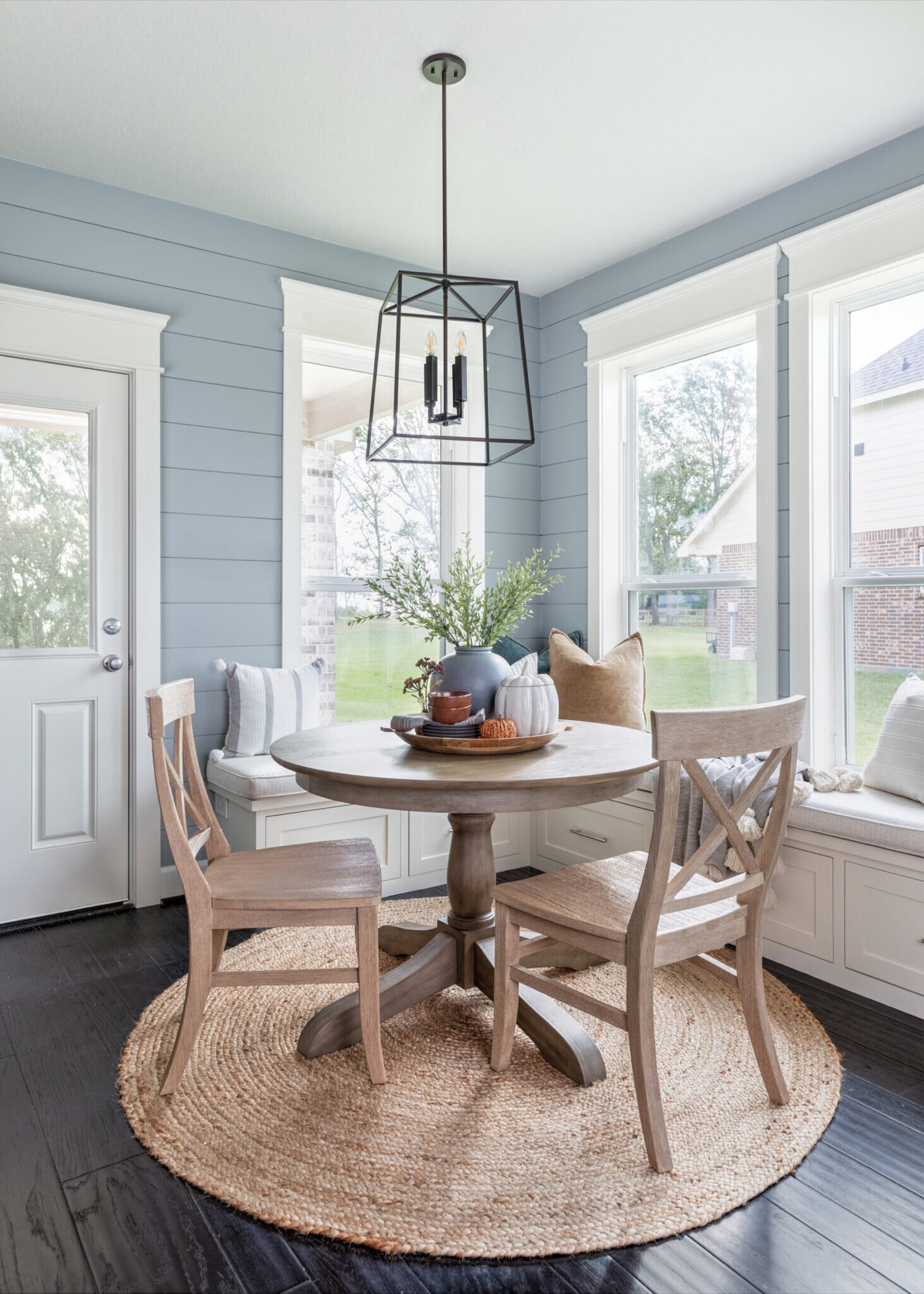 Breakfast nook with dusty blue shiplap, a round jute rug and whitewashed X-back chairs in the Silver Moon project by Jennifer Kizzee Design