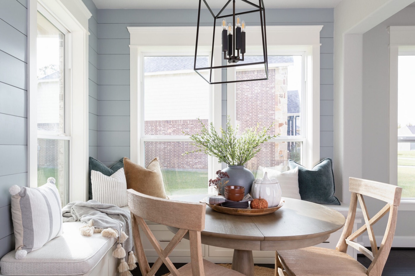 Built-in window bench layered with teal and camel velvet pillows under a black iron lantern in the Silver Moon project by Jennifer Kizzee Design