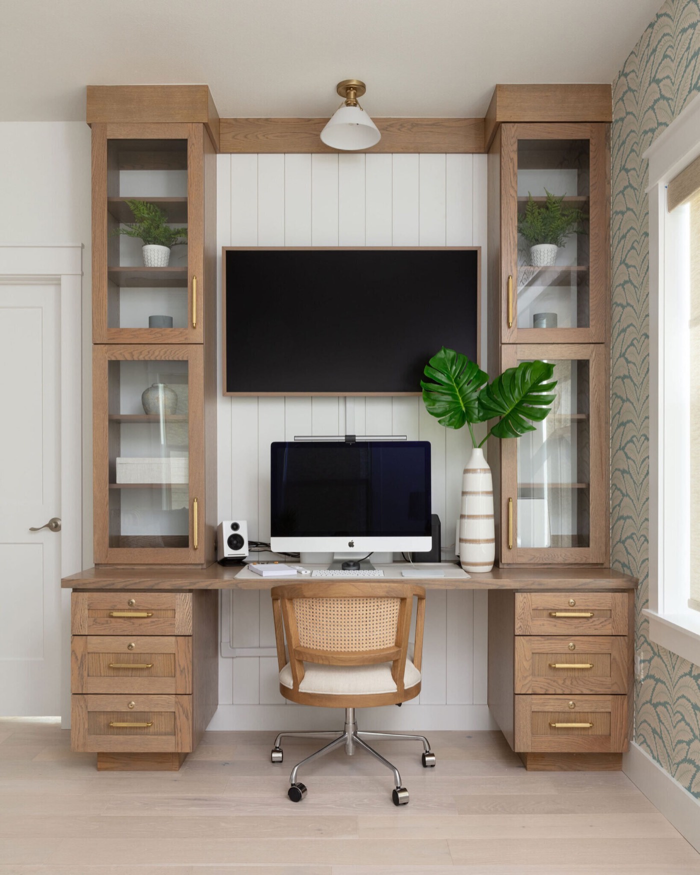 Built-in white oak desk with glass-front upper cabinets and brass drawer pulls in the Starfish Vacation Home project by Jennifer Kizzee Design