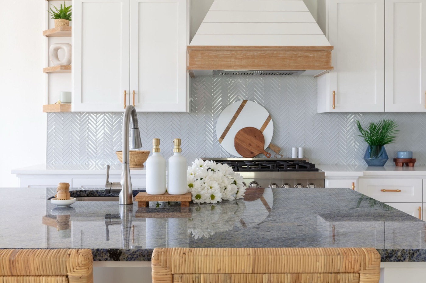 Blue granite island countertop against a herringbone tile backsplash and brass cabinet hardware in the Starfish Vacation Home project by Jennifer Kizzee Design