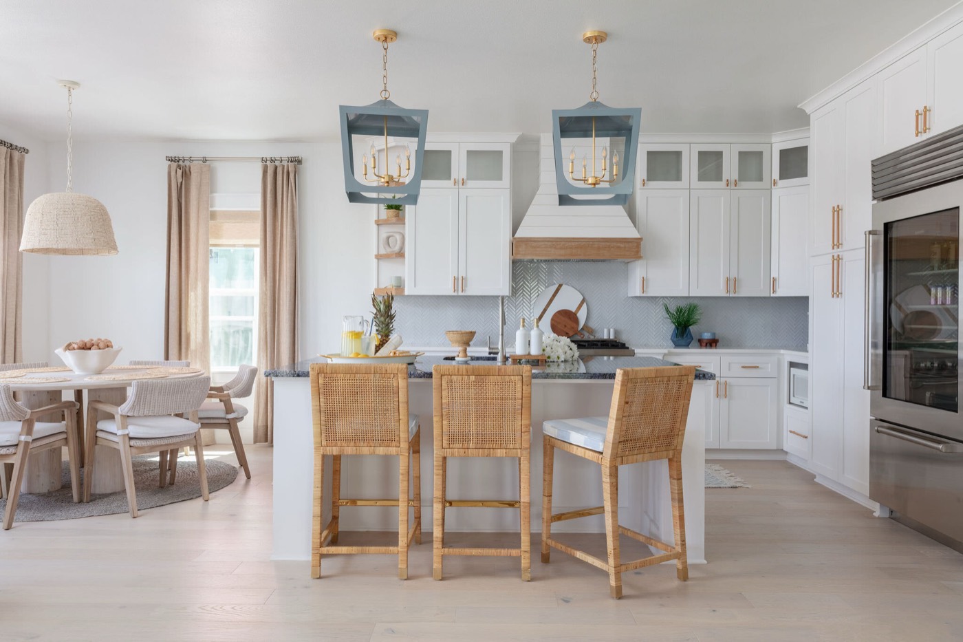 Kitchen with slate blue lantern pendants, a white oak and shiplap range hood, and rattan counter stools in the Starfish Vacation Home project by Jennifer Kizzee Design