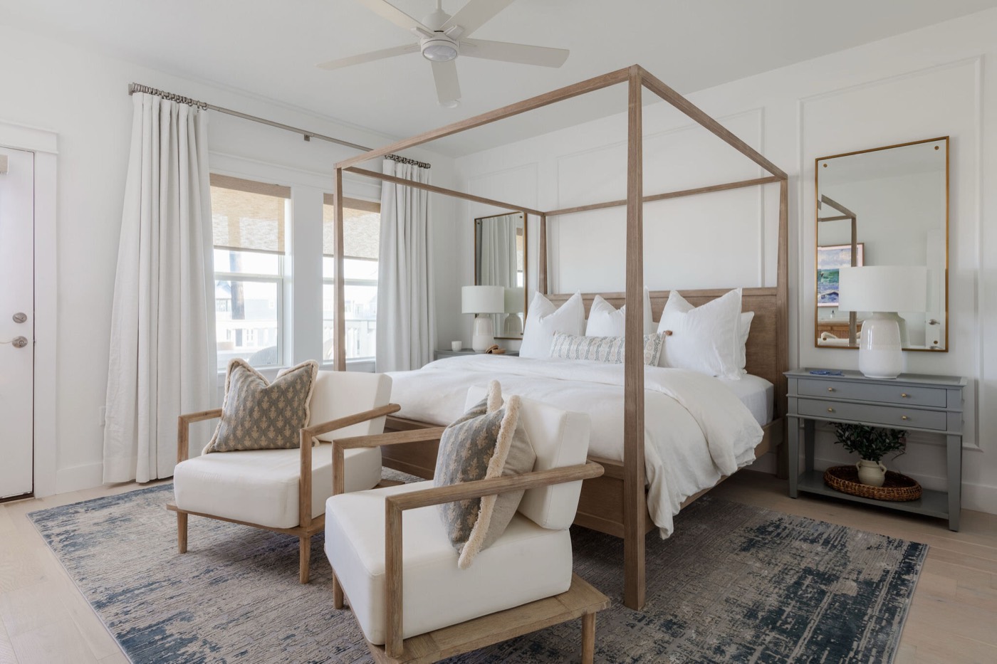 Primary bedroom with a white oak canopy bed against board and batten walls and blue gray nightstands in the Starfish Vacation Home project by Jennifer Kizzee Design