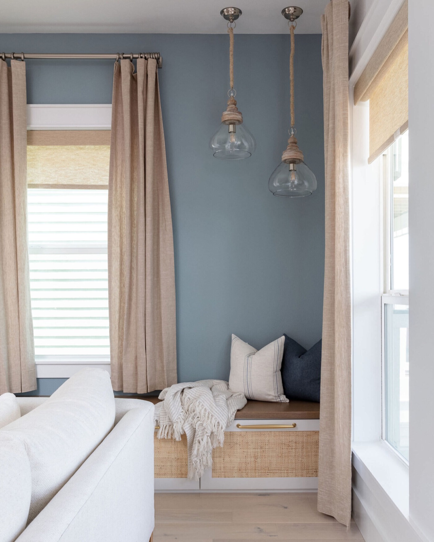 Window seat with a cane front panel lit by two rope-wrapped glass pendants in the Starfish Vacation Home project by Jennifer Kizzee Design