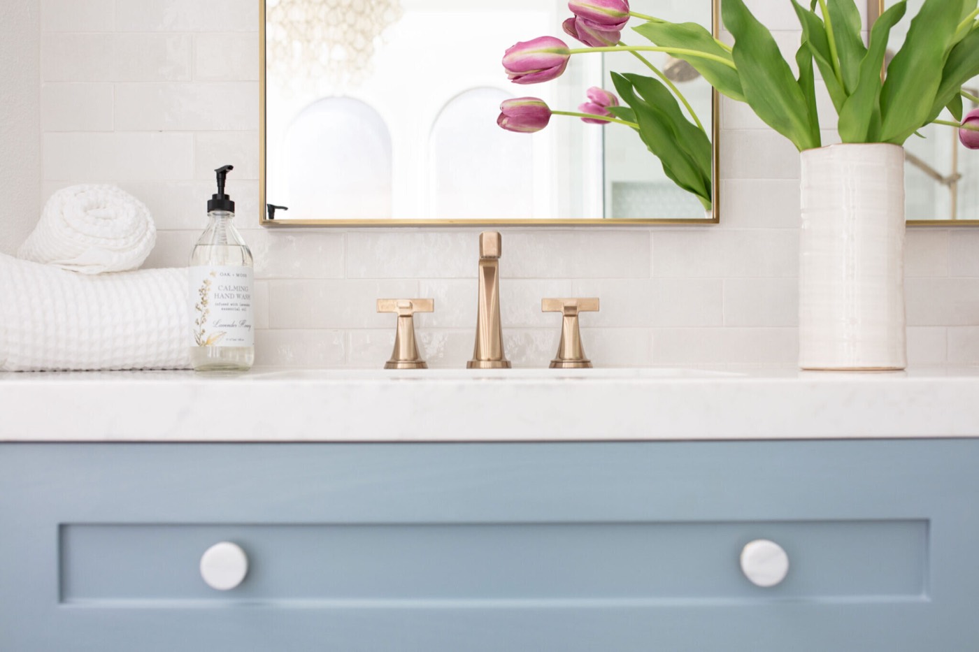 Champagne bronze widespread faucet with cross handles on a white marble counter in the Sunstream Bath project by Jennifer Kizzee Design