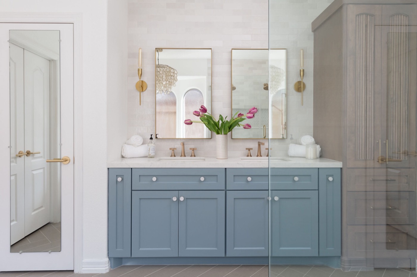 Dusty blue double vanity with ceramic knobs and champagne bronze fittings in the Sunstream Bath project by Jennifer Kizzee Design