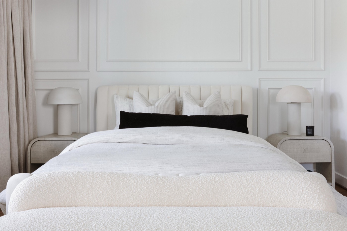 Bedroom with an applied molding panel wall, cream channel-tufted headboard, and twin mushroom lamps in the Vue Point project by Jennifer Kizzee Design