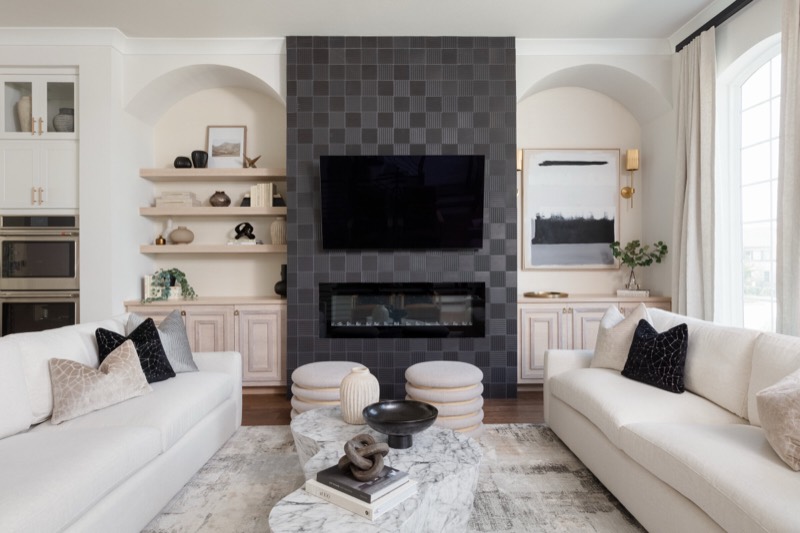 Living room with a charcoal grid-tile fireplace wall in the Vue Point project by Jennifer Kizzee Design in The Woodlands, Texas